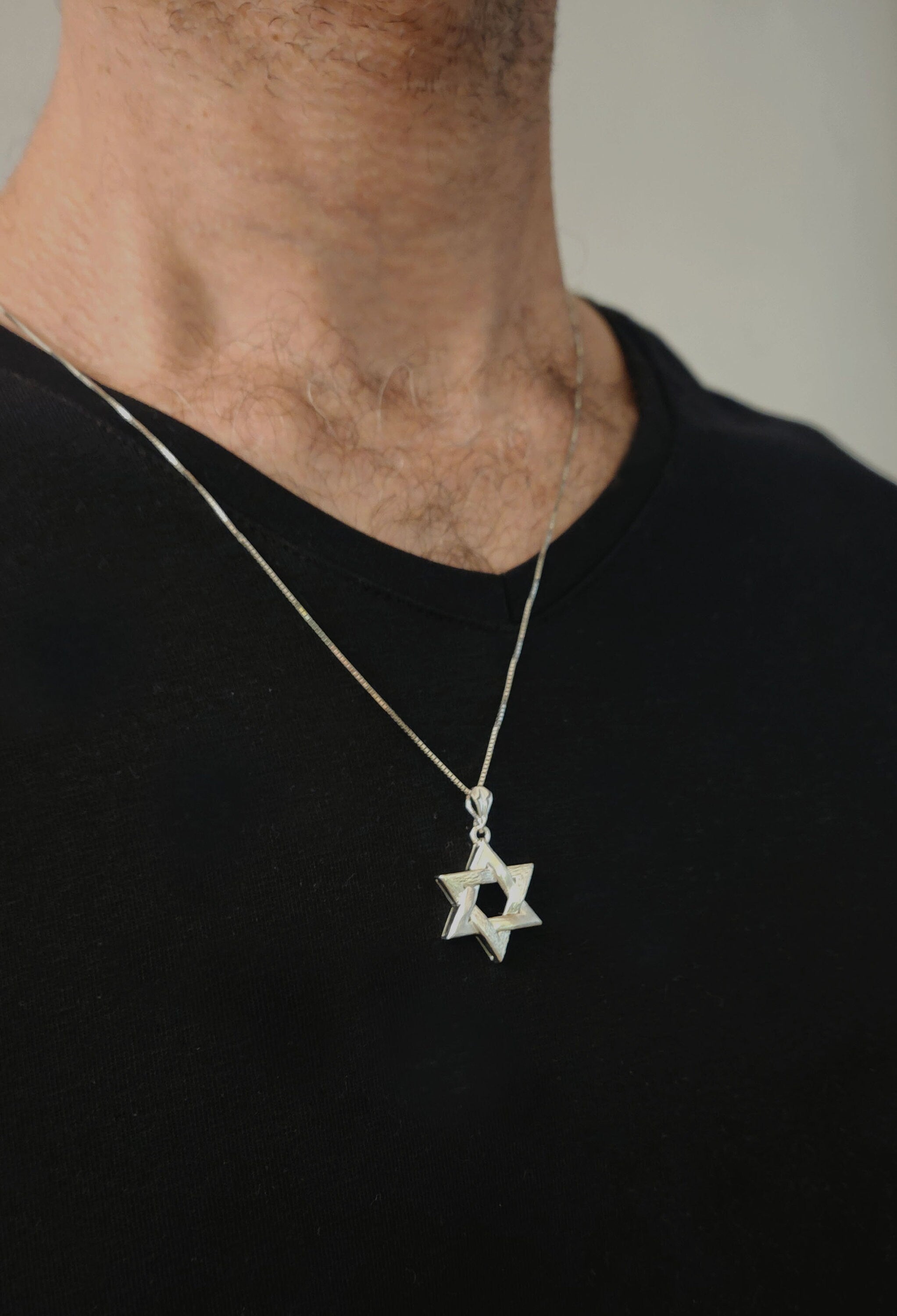 a man wearing a star of david necklace
