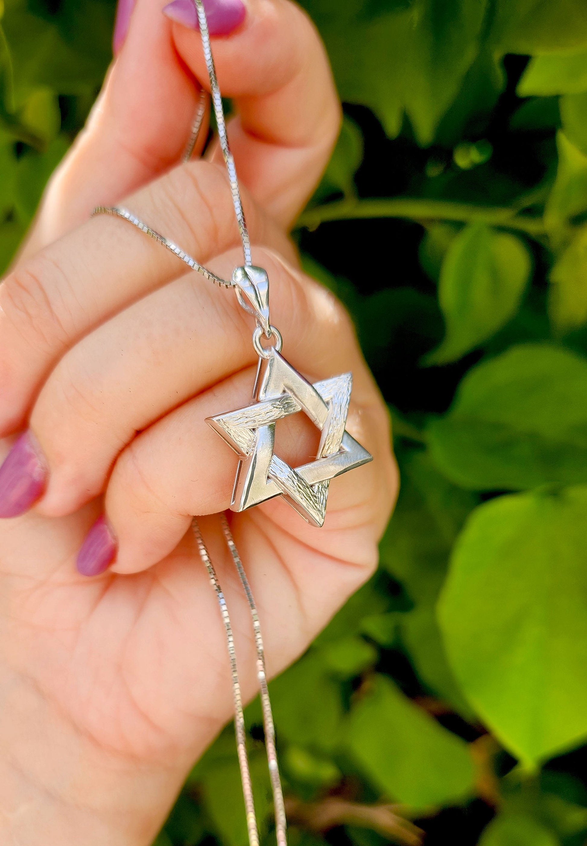 a woman holding a star of david necklace