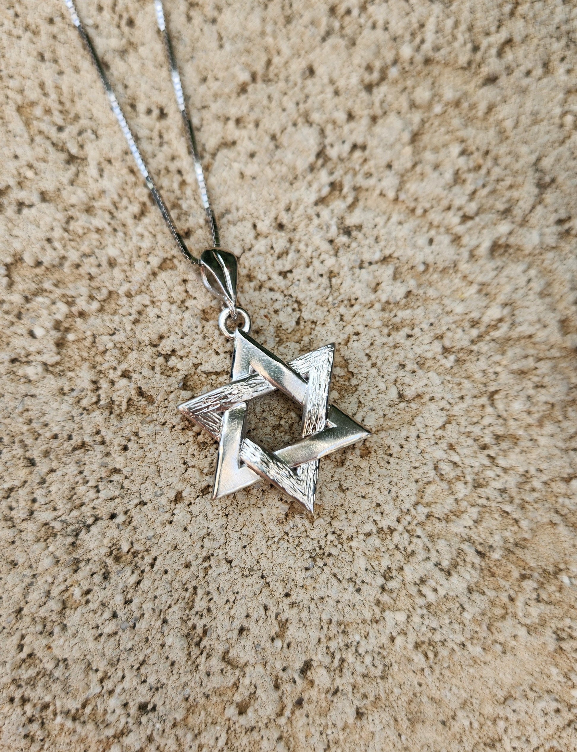 a silver star of david pendant on a chain