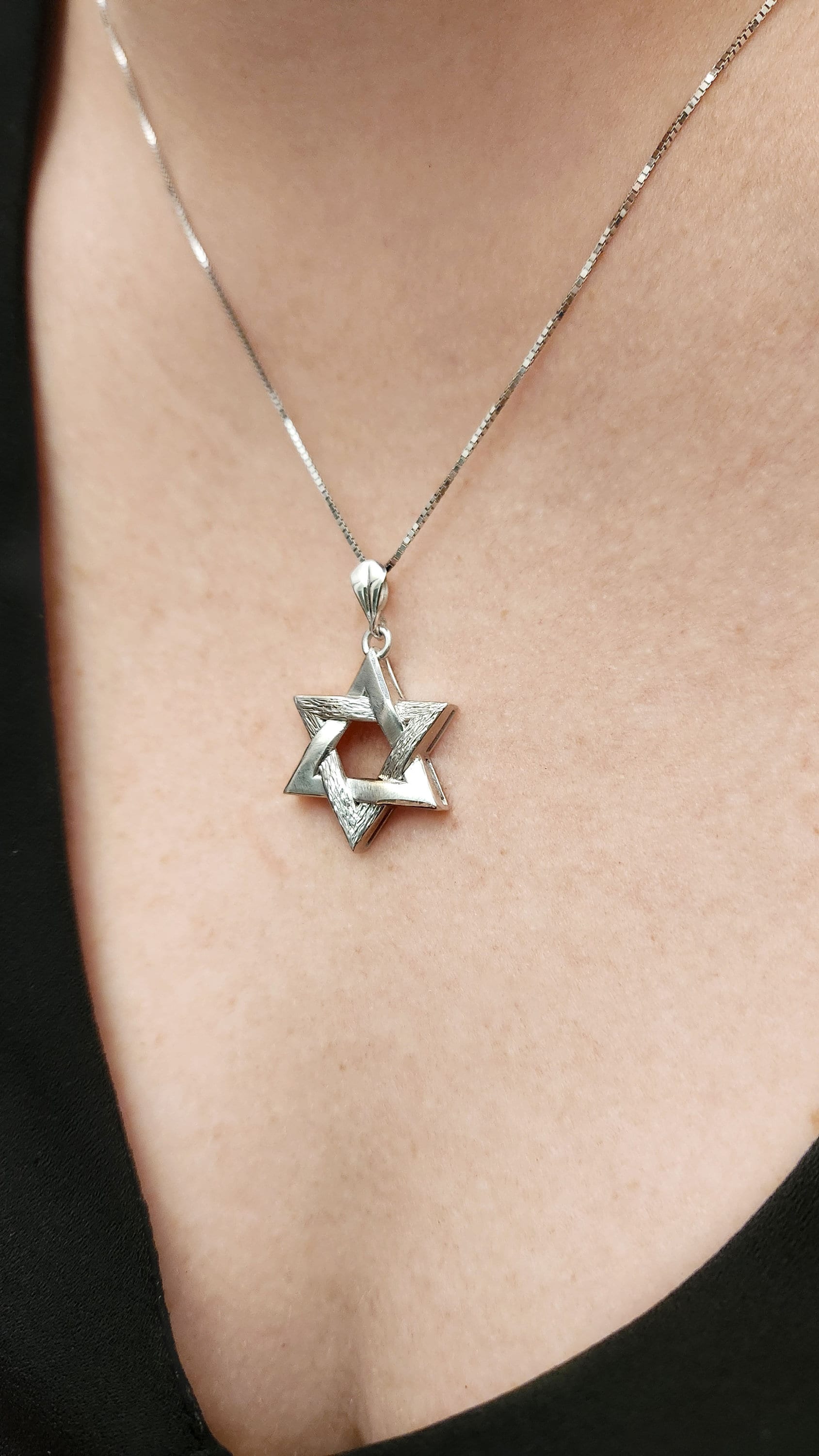 a woman wearing a necklace with a star of david on it