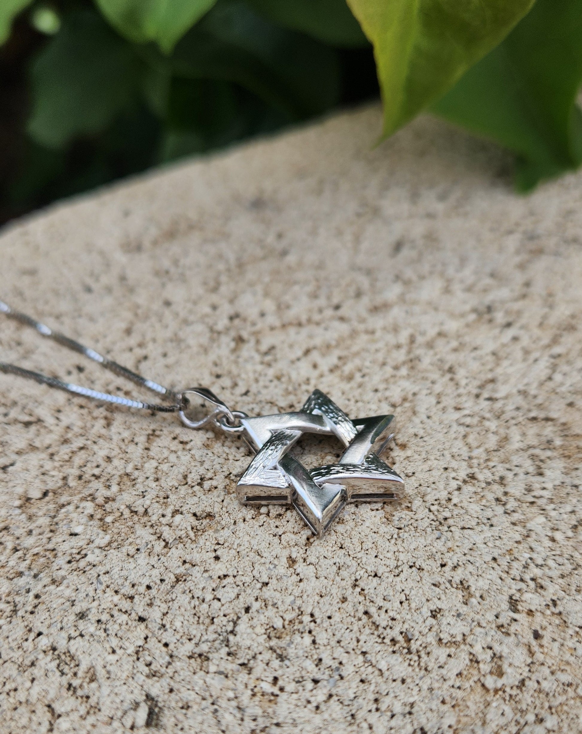 a star of david necklace on a stone surface